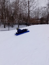 Lapsi laskemassa mäkeä isolla liukurilla.