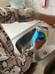 Lapsi huuhtelee maitopurkkia.