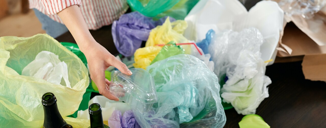 Ihminen lajittelee erilaisia jätteitä pusseihin
