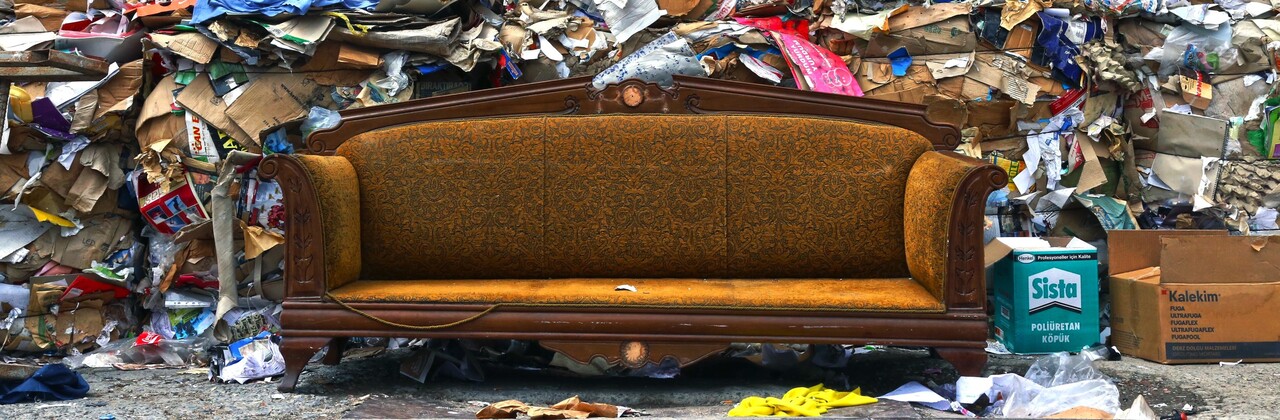 Vanha sohva jätekasan edustalla