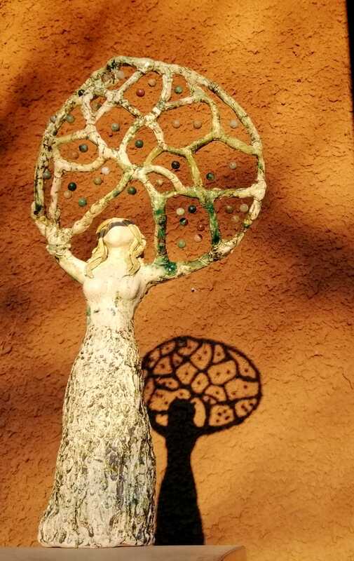 Keraaminen naispatsas, joka pitelee päänsä päällä helmiverkkoa, josta heijastuu kaunis varjo taakse