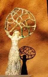 Keraaminen naispatsas, joka pitelee päänsä päällä helmiverkkoa, josta heijastuu kaunis varjo taakse