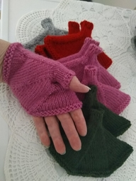 Pinkki kämmekäs paikallaan kädessä ja taustalla monta paria erivärisiä, saman mallisia kämmekkäitä.