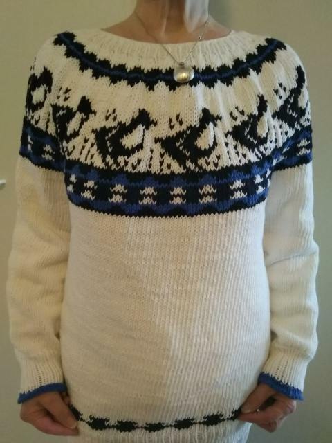 Valkoinen villapusero, jossa kirkkaan- ja tummansinisävyinen kaarroke, hihansuut ja helma.