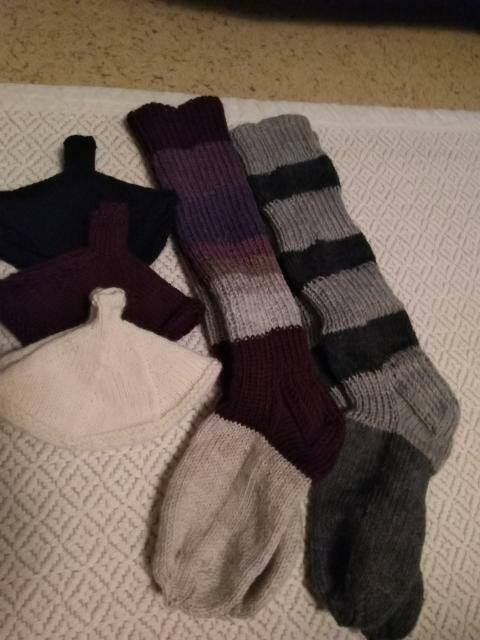 Kahdet pitkävartiset, raidalliset villasukat ja kolmet kämmekkäät.