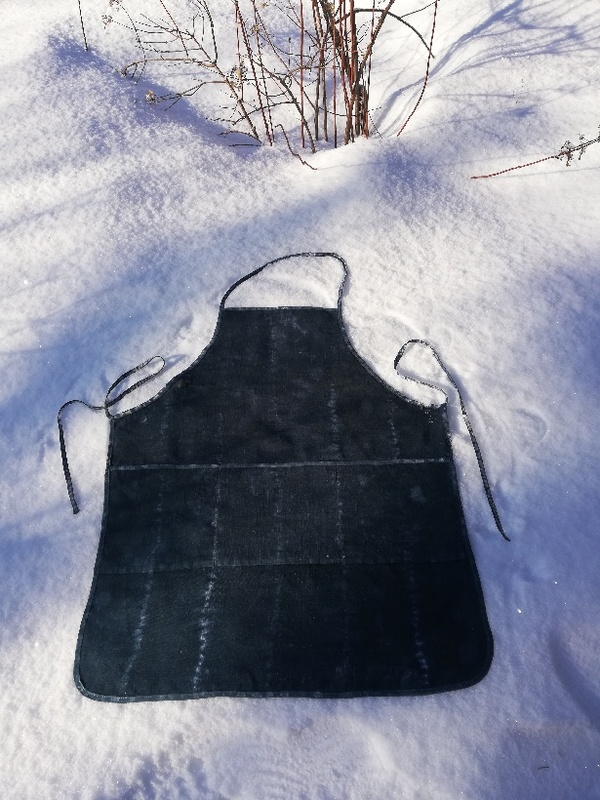 Tumman sävyinen esiliina, johon värjäämällä saatu ruutumainen vaaleampi kuvio.