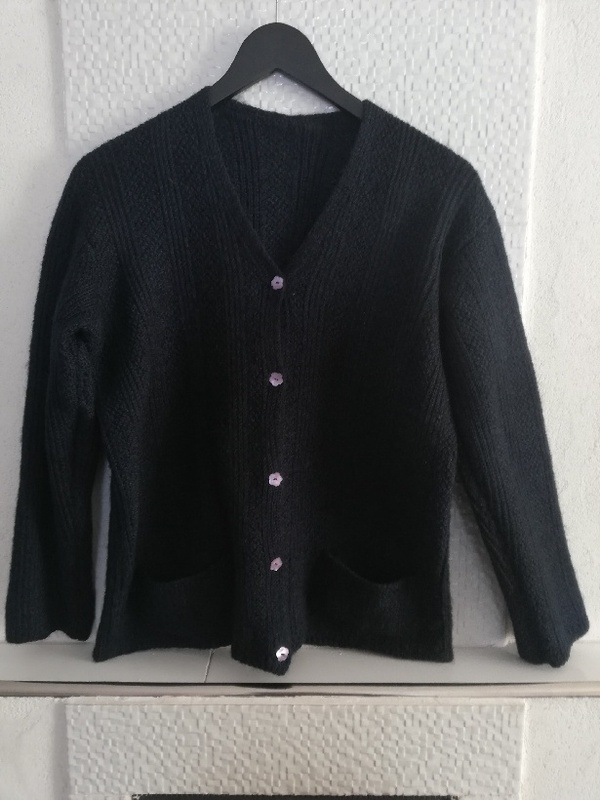 Tummansininen villatakki, jossa helmiäisnapit.