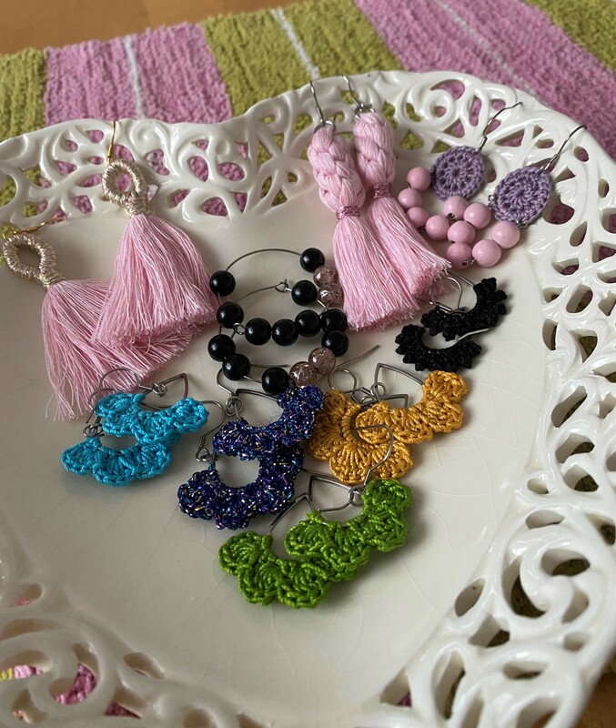 Värikkäitä, virkkaamalla, solmeilemalla ja helmistä valmistettuja korvakoruja vadilla