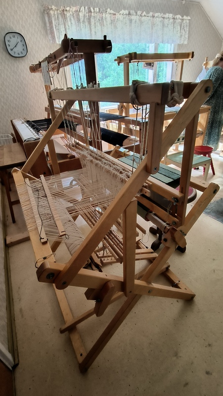 Huoneessa useita kangaspuita, taustalla ikkuna, josta näkyy metsämaisema