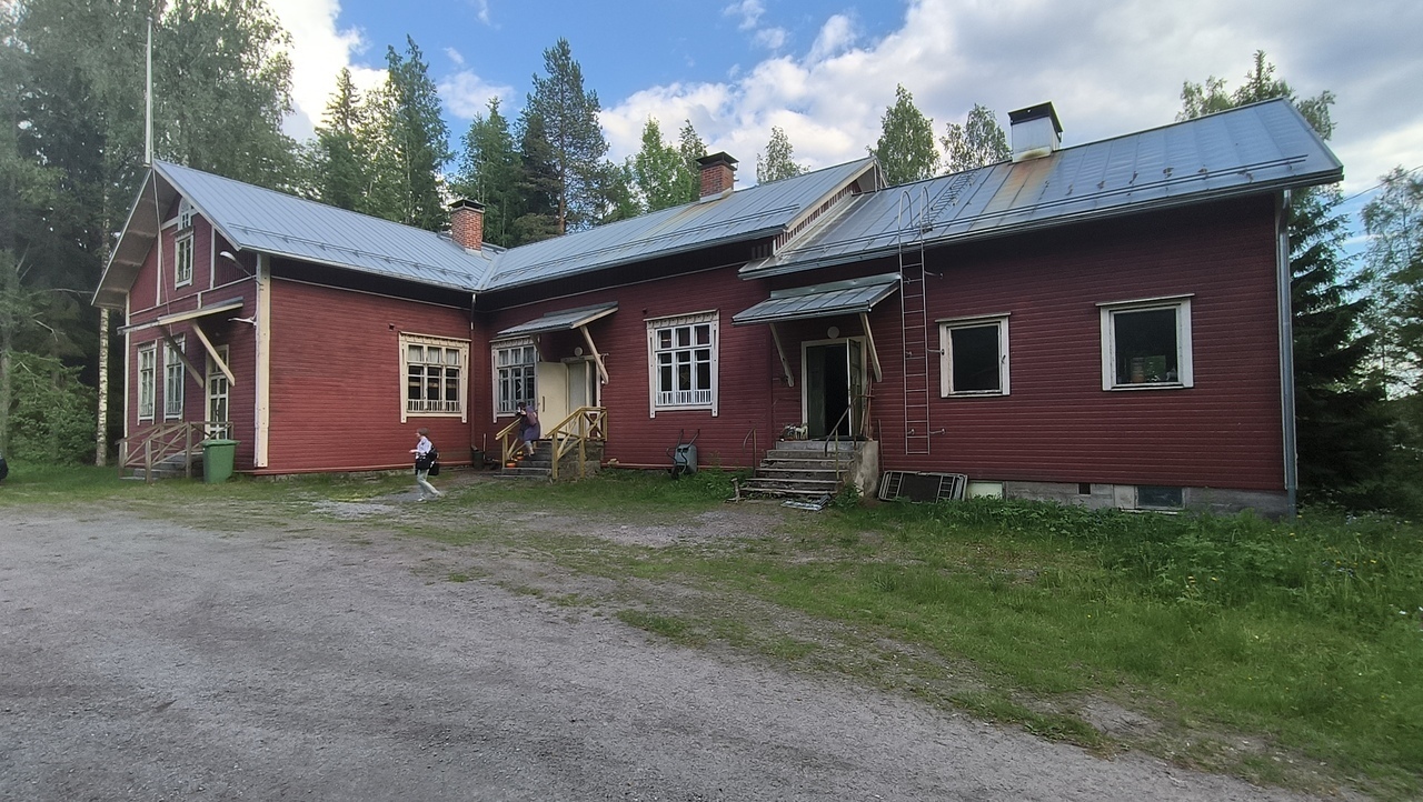 Punainen puinen kaksikerroksinen entinen koulurakennus