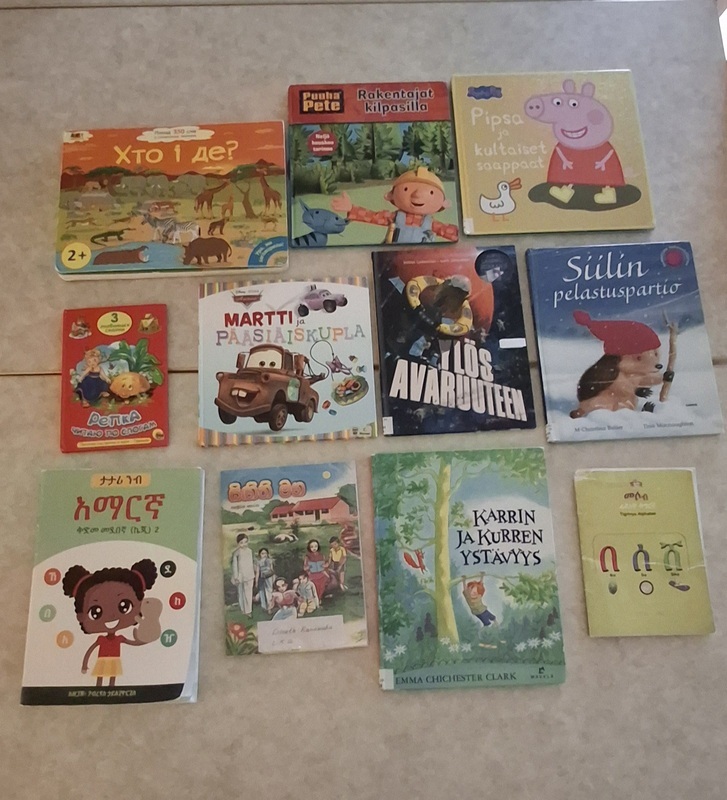 20250221_105437.jpg Kuva kirjoista pöydällä. Kirjoja eri kielillä, mm. suomeksi, venäjäksi ja amharaksi.