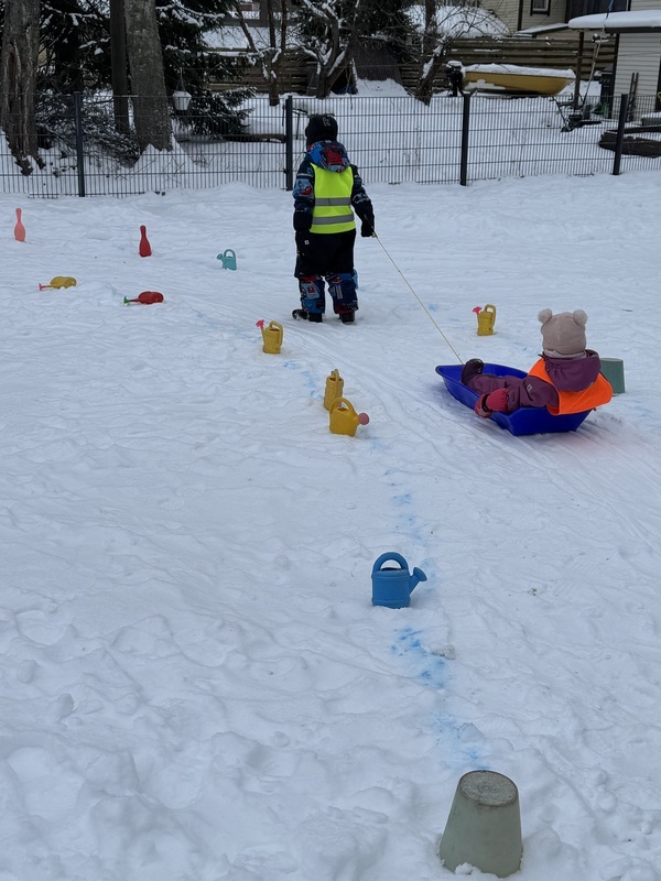 Isompi lapsi vetää pienempää pulkassa