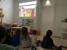Lapset katsovat elokuvaa ja kuvassa on mies ja kaksi lasta