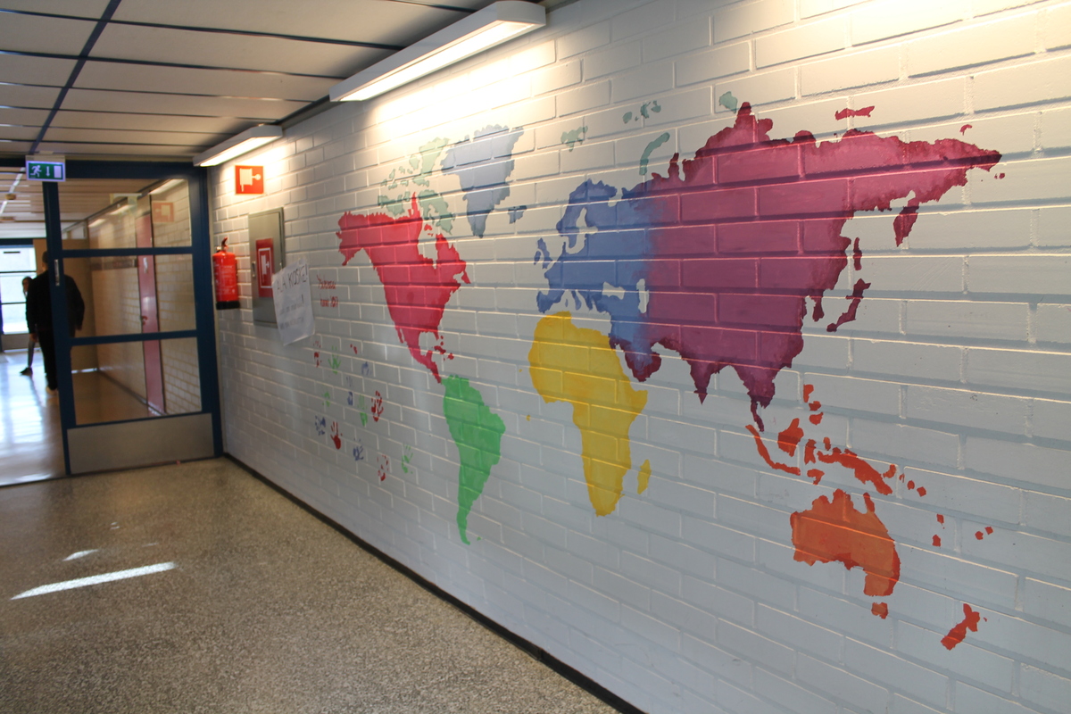 Kuvassa oppilaiden maalaama värikäs maailmankartta koulun seinällä.