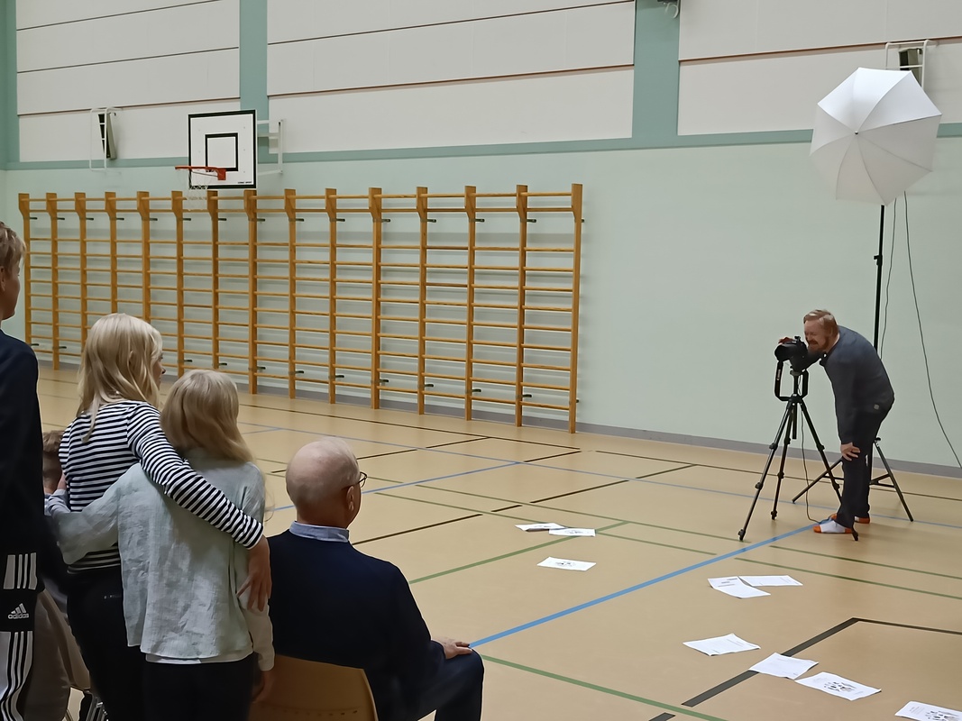 Valokuvaaja valmistautuu ottamaan luokkakuvaa Utin koulun liikuntasalissa.
