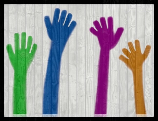 Lautaseinään maalattuja värikkäitä käsien kuvia.