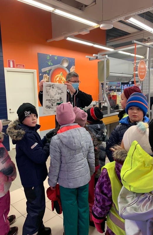 Kuvassa K-kauppias esittelee oppilaiden suunnittelemaa muovikassia