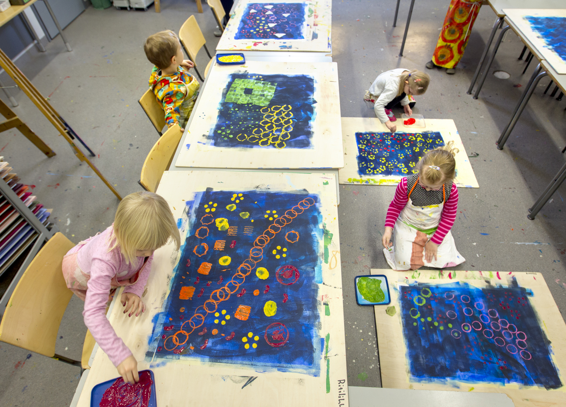Lapsia maalamassa työpöydän ympälillä