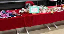 Punaisilla pöytäliinoilla koristeltu pöytä, jonka päällä villasukkia ja leivonnaisia.