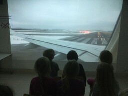 Lapset katsovat yhdessä isolta ruudulta lentokoneen kuvaa.