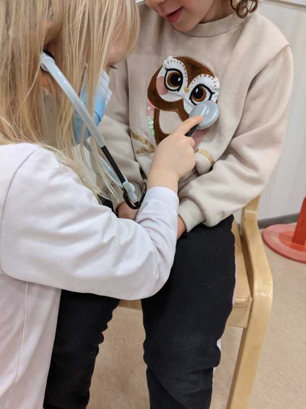 Lapsi leikkii lääkäriä. Hän kuuntelee stetoskoopilla potilaan sydäntä.