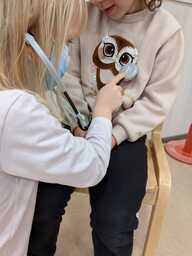 Lapsi leikkii lääkäriä. Hän kuuntelee stetoskoopilla potilaan sydäntä.