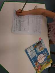 Oppilas täyttää tehtävämonistetta lyijykynällä. Kuva otettu ylhäältä päin, oppilaan kasvot eivät näy.