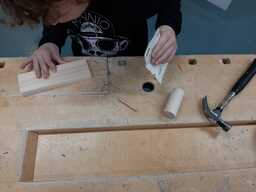 Lapsi hioo puuta hiomapaperilla höyläpenkin äärellä.