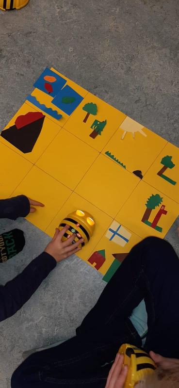 Lapset laittavat ampiaisrobotti beebotin liikkeelle robotin toimintamatolla lattialla.