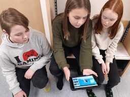 Oppilaat istuvat penkillä ja katsovat yhdessä iPadilta annettua tehtävää.