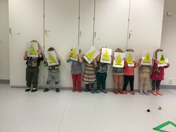 Lapset seisovat rivissä keltainen viiri kasvojen edessä.