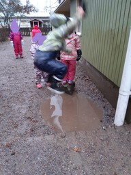 Lapsi hyppää vesilätäkköön.