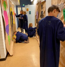 Nuoret maalaavat seiniä koulun käytävällä.