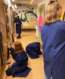 Nuoret maalaavat seiniä koulun käytävällä.