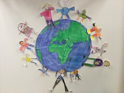Kuvassa on lasten tekemä maapallo, jonka ympärille on leikattu paperisia ihmishahmoja.