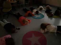 Oppilaat makaavat mahallaan hämärässä huoneessa silmät ummistettuna. Kuva otettu ylhäältä päin.