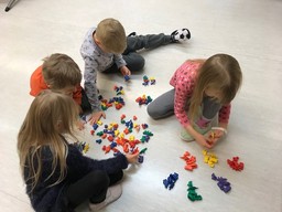 Neljä lasta lajittelee muovihahmoja värien perustella muovihahmokasoista.