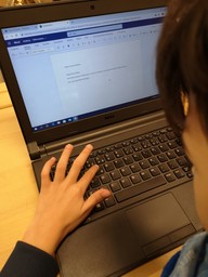 Kuva otettu oppilaan niskan takaa, kuvassa näkyy että oppilas näppäilee Chromebookia.