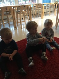 Kolme lasta istuu lattialla vierekkäin ja keskustelevat.