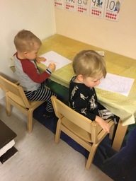 Kaksi lasta piirtää pöydän ääressä.