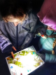 Oppilas tutkii karttaa otsalampun valossa.