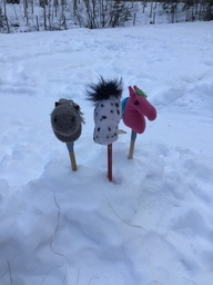 Lumihangessa pystyssä kolme keppihevosta.