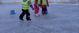 Kolme laista luistelemassa, kuva rajattu niin että lapsilta näkyvät vain jalat.