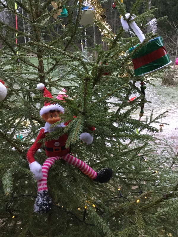 Minni-tonttu roikkuu kuusessa joulukoristeiden seassa.