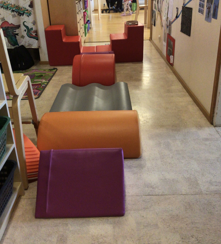 Päiväkodin käytävä, jossa isoja erivärisiä palikoita jonossa.