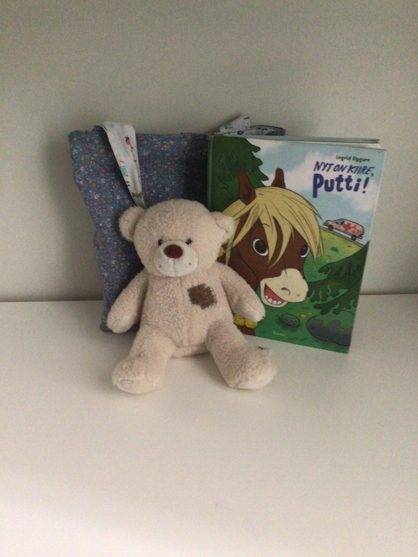 Kuvassa nalle, kirja ja sininen kassi.