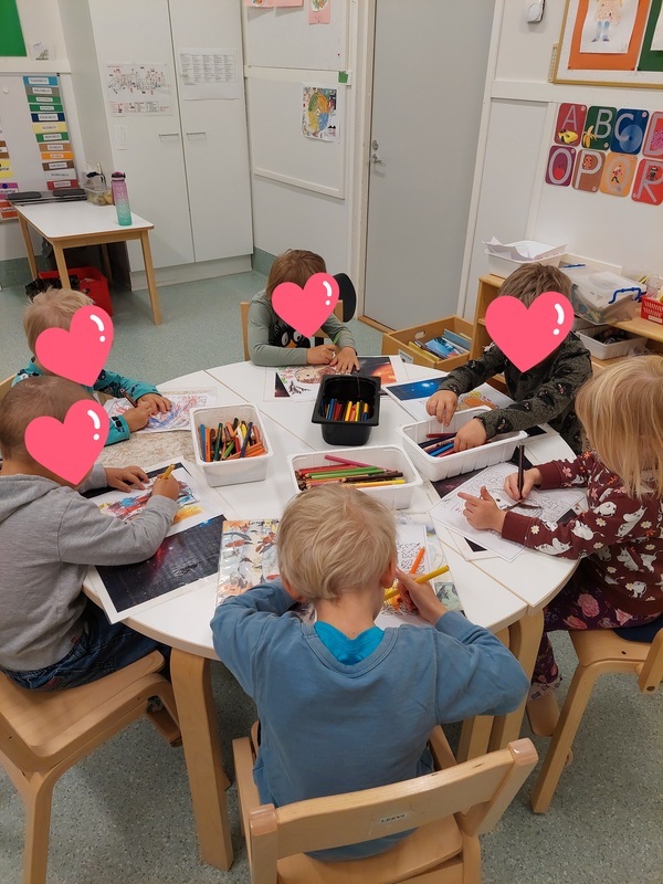 Lapset värittävät värityskuvia pöydän ääressä.