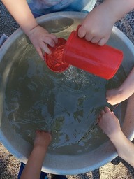 Kädet vedessä ja kaatamassa kannusta vettä.