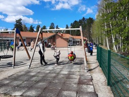Lapsia keinumassa ja aikuinen vahtii.