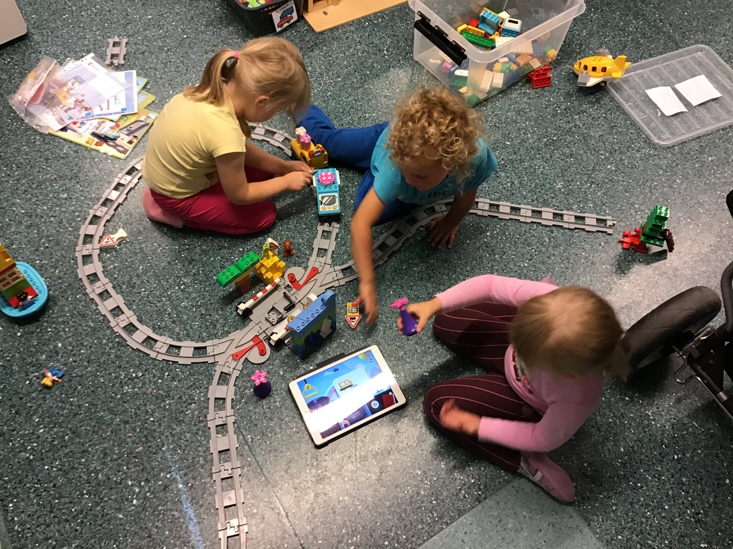 Lapset ovat rakentaneet lego junaradan ja ohjaavat junaa ipadilla kulkemaan rataa pitkin.
